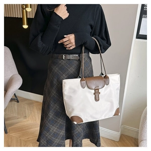 Detail of a large beige and brown tote bag showing the color contrast and leather handles