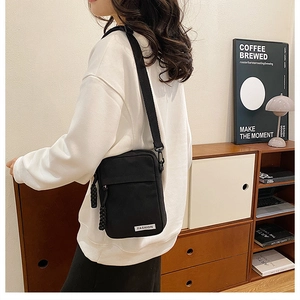 Close-up detail of black canvas crossbody bag showing Fashion label and adjustable strap