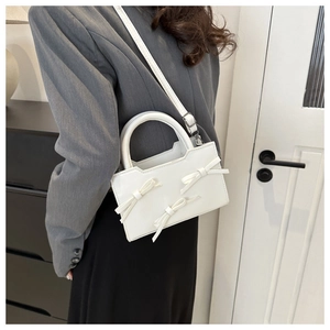 Vue détaillée du sac à bandoulière blanc orné de trois nœuds décoratifs élégants