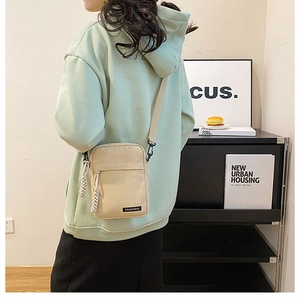 Detail of beige canvas crossbody bag with Fashion label and woven rope zipper pull