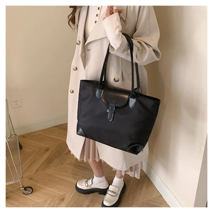 Detailed view of black tote bag with nylon fabric and leather handles on model
