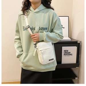 Detail of white canvas crossbody bag with black zipper pocket and fashion label