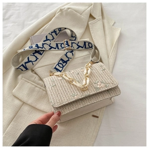 Détails d'un sac en paille tressée avec broderie florale et bandoulière large