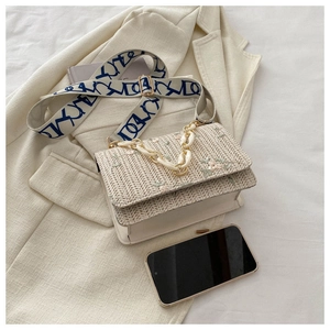 Détail du sac en paille avec broderie florale et chaîne acrylique sur blazer beige