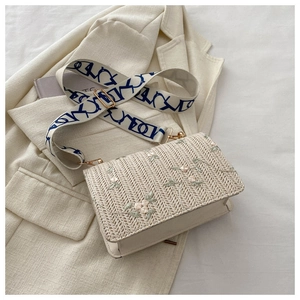 Gros plan du sac tissé crème avec broderie florale et large bandoulière géométrique