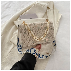 Détail du sac tissé avec broderies florales, chaîne en acrylique et large bandoulière