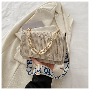 Détail du sac en paille avec broderie florale et large bandoulière bohème
