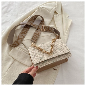 Détail de broderie florale sur sac bandoulière en paille avec chaîne acrylique