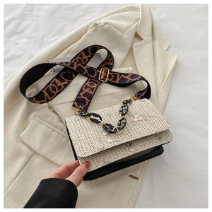 Détail du sac en paille tissée avec broderie florale et large bandoulière à motifs