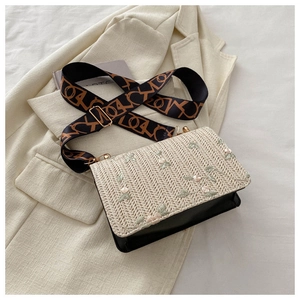 Détail du rabat en paille avec broderie florale et large bandoulière à motifs géométriques