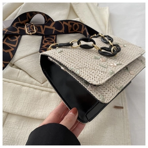 Détail du petit sac bandoulière en paille avec broderie florale et chaîne en acrylique