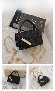 Detail view of mini black glitter crossbody bag with gold chain strap and metal bar