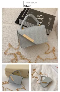 Detailed macro view of a silver woven handbag with gold metal bar and chain strap