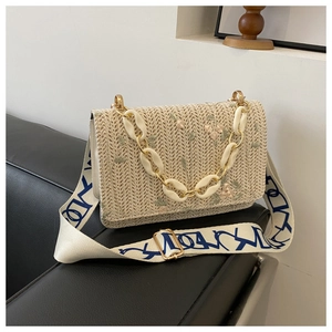 Détail du sac bandoulière en paille avec broderie florale et chaîne acrylique