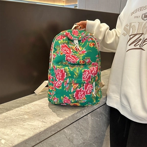 Close-up of green floral canvas backpack with pink peony patterns on marble table