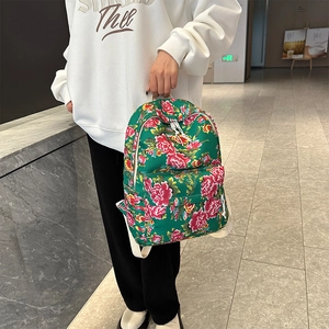 Detail of green floral backpack featuring traditional red peony patterns and zip pocket