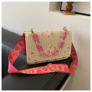 Détail de broderie florale sur un sac en paille avec bandoulières acrylique et toile