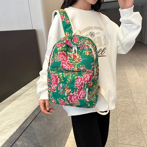 Detail view of a green floral backpack with vibrant red peony patterns and cream straps
