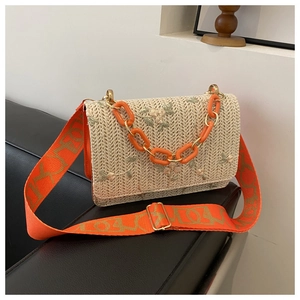 Détail du sac bandoulière en paille avec broderie florale et chaîne acrylique orange