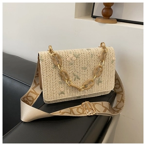 Détail de broderie florale sur sac en paille avec chaîne acrylique et bandoulière