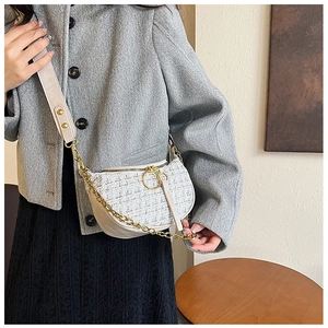 Detail view of tweed fabric stitching and golden ring zipper on off-white crossbody bag