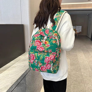 Detail of green floral backpack with red peony pattern and front zipper pocket