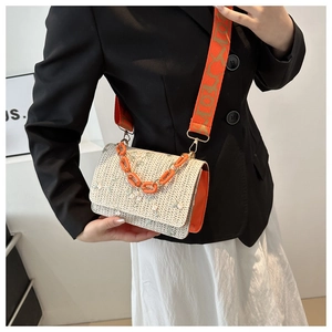 Détail du sac bandoulière en paille avec broderie florale et chaîne en acrylique orange