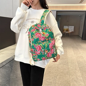 Detail of green floral canvas backpack with red peony pattern and beige shoulder straps