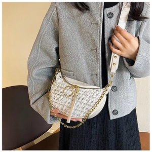 Detail of tweed crescent bag featuring gold chain strap and textured woven fabric