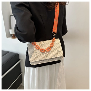 Détail de la broderie florale et chaîne acrylique orange sur sac en paille tissé