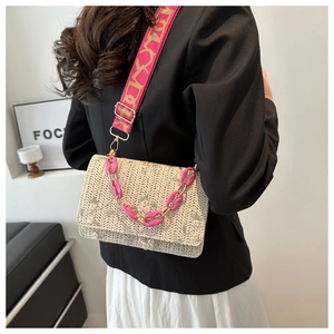 Détail du sac bandoulière en paille avec chaîne acrylique rose et broderie florale