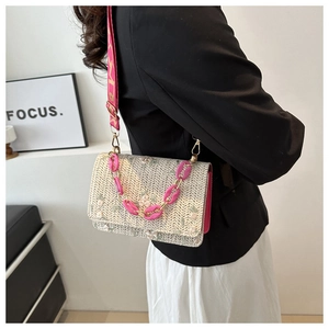 Détail du sac en paille tressée avec broderie florale et chaîne en acrylique rose