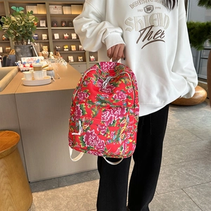 Detail of red floral backpack with traditional peony patterns held by hand in a minimalist shop