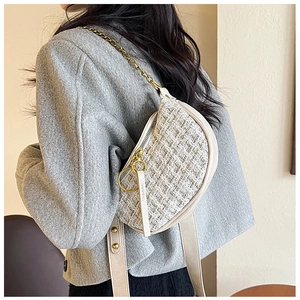 Detail of tweed dumpling bag with golden chain strap and leather handle on a grey coat