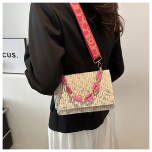 Détail du sac en paille avec broderie florale et chaîne en acrylique rose porté par mannequin