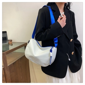 Close-up of a white half-moon shoulder bag featuring a vibrant blue nylon strap and zipper