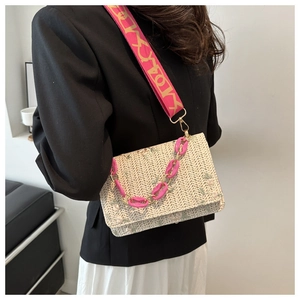 Détail du sac en paille tissée avec broderie florale verte et chaîne en acrylique rose