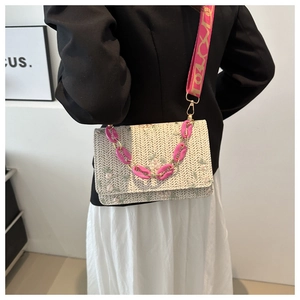 Détail du sac à rabat en paille tissée avec broderie florale et chaîne en acrylique