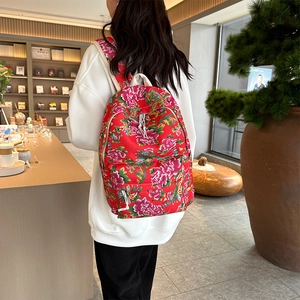 Detail of red floral canvas backpack featuring traditional Chinese peony pattern and straps