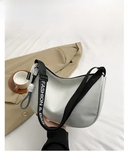 Detail view of crescent shoulder bag with white body and black FASHION lettered strap