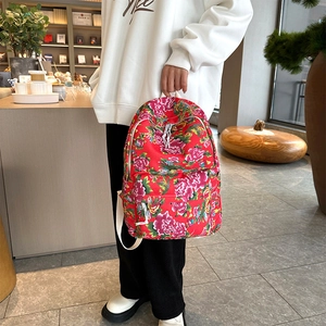 Detail view of ethnic peony floral pattern on a red canvas backpack with white zippers