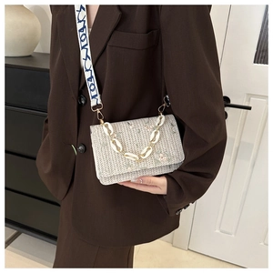 Détail du sac bandoulière en paille crème avec broderie florale et large sangle à motifs