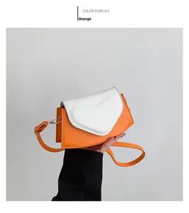 Détail du sac bandoulière orange avec rabat coeur blanc et texture en cuir PU lisse