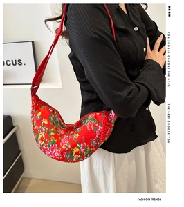 Detail of red floral crescent bag featuring traditional peony patterns and woven zipper knot