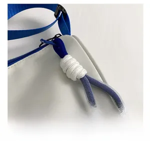 Detail of blue and white woven zipper puller on a minimalist white shoulder bag