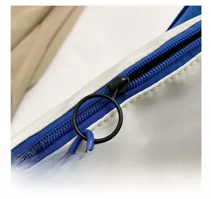Detail shot of smooth blue zipper with round black pull ring on a white fabric bag