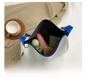 Detail showing high-capacity white shoulder bag with blue zipper and internal compartments