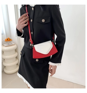 Détail du sac à bandoulière en forme de cœur rouge et blanc porté sur une tenue noire