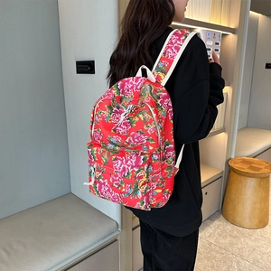 Close-up of red floral backpack showing Chinese peony pattern and white straps