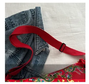 Detail of wide adjustable shoulder strap on red floral ethnic crossbody bag